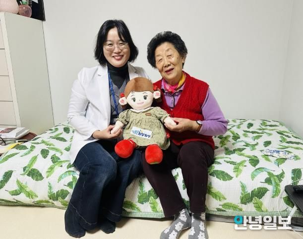 화성시동탄보건소 관계자와 독거 어르신이 AI 돌봄로봇 ‘효돌이’를 함께 들고 환하게 웃고 있다